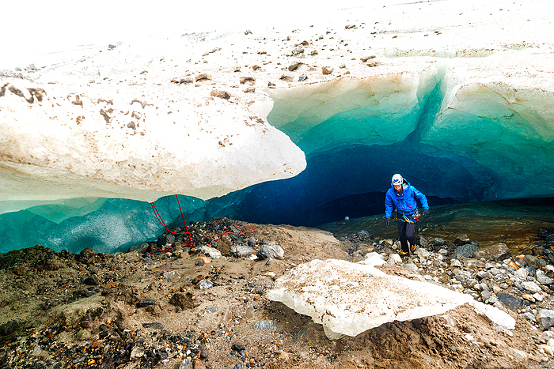 Male guide prepares rappel rope for particpants to explore an ice cave on a 