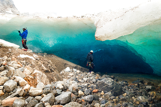 Male guide prepares rappel rope for particpants to explore an ice cave on a 