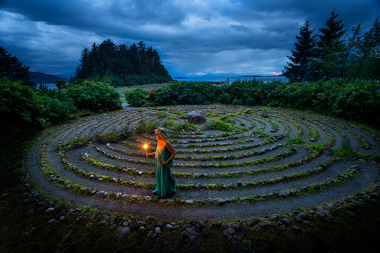 Woman walks around the Love Labyrinth with a lit candle at night, Shrine to St Terese, Juneau, Alaska