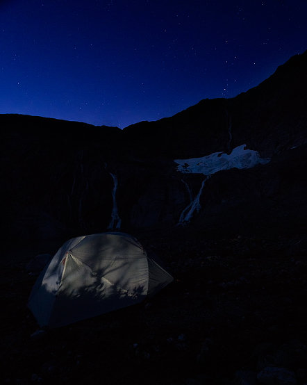 Night stars over waterfalls and tent on Lemon Glacier, Juneau Icefield, Juneau, Alaska, USA