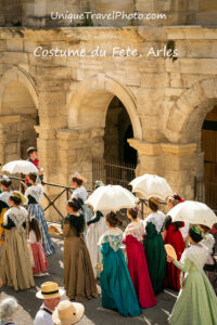 Fete du Costume passing by the ancient Roman Arena. Over 500 women dress in traditional attire from their region depicting differing lace and hats in this annual summer festival, Arles, France, Europe